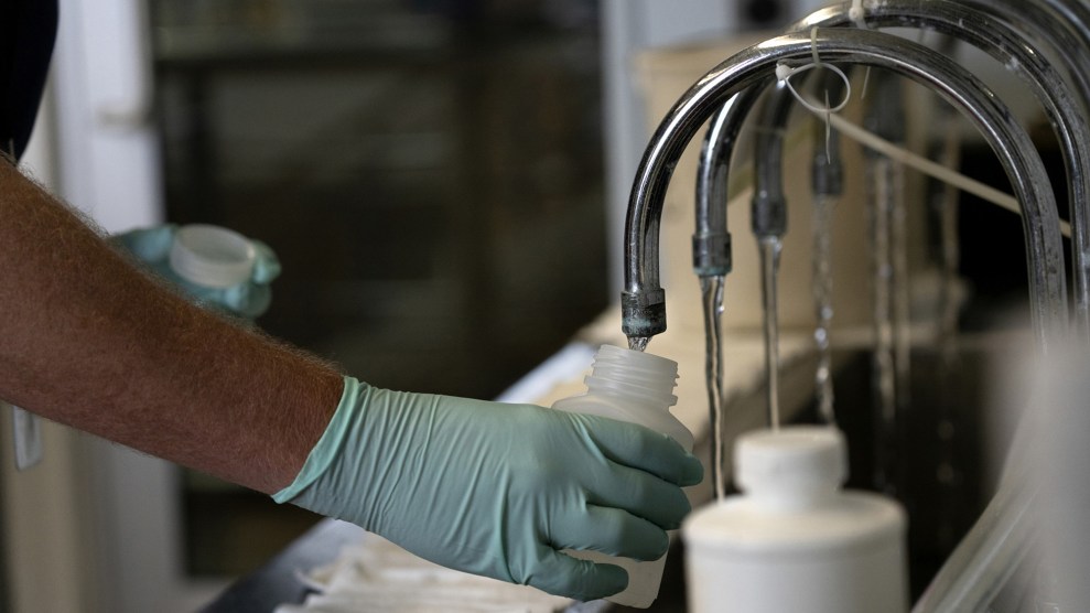 A hand holds a bottle under a metal tap.