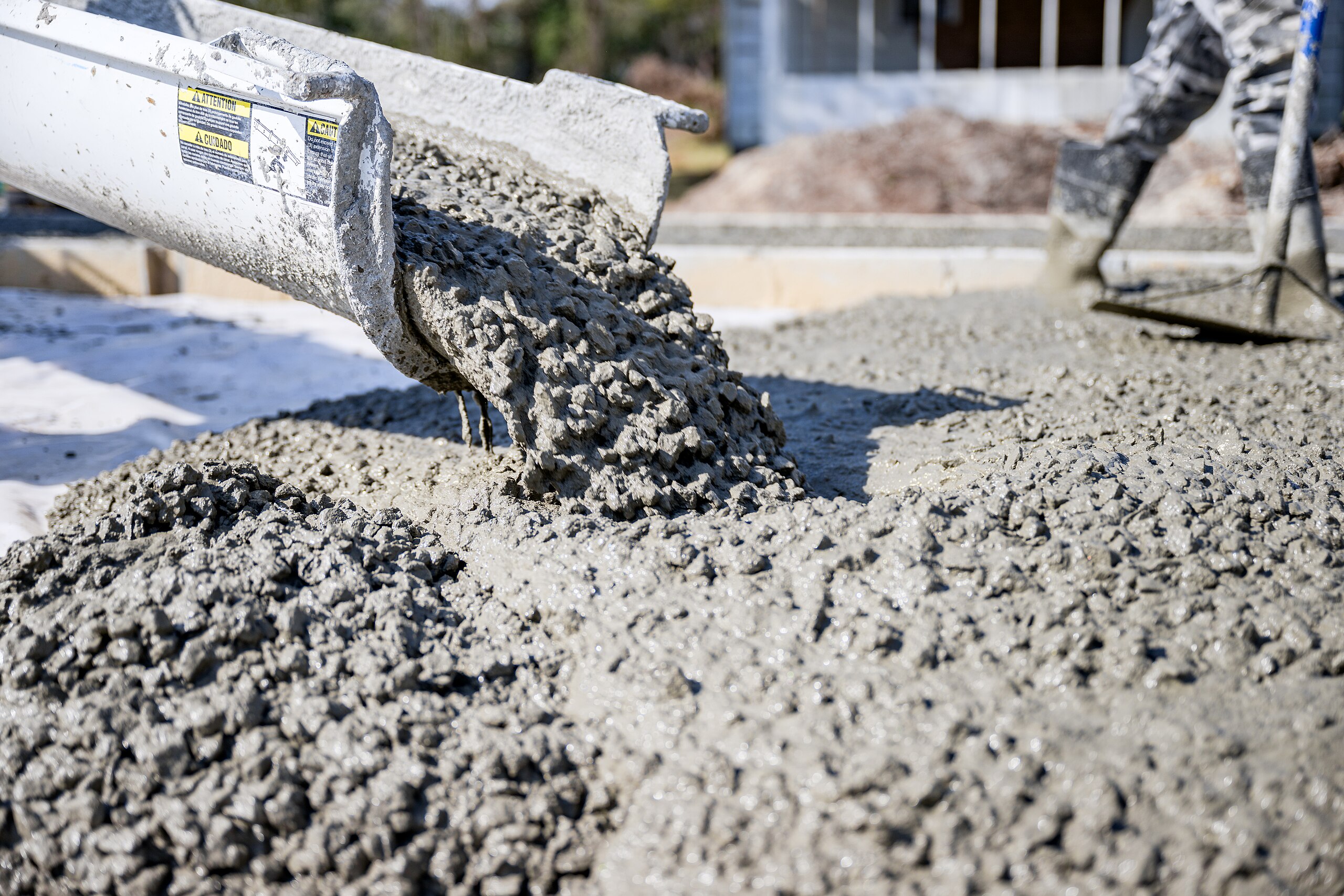 Concrete flows from a half-tube into the ground.