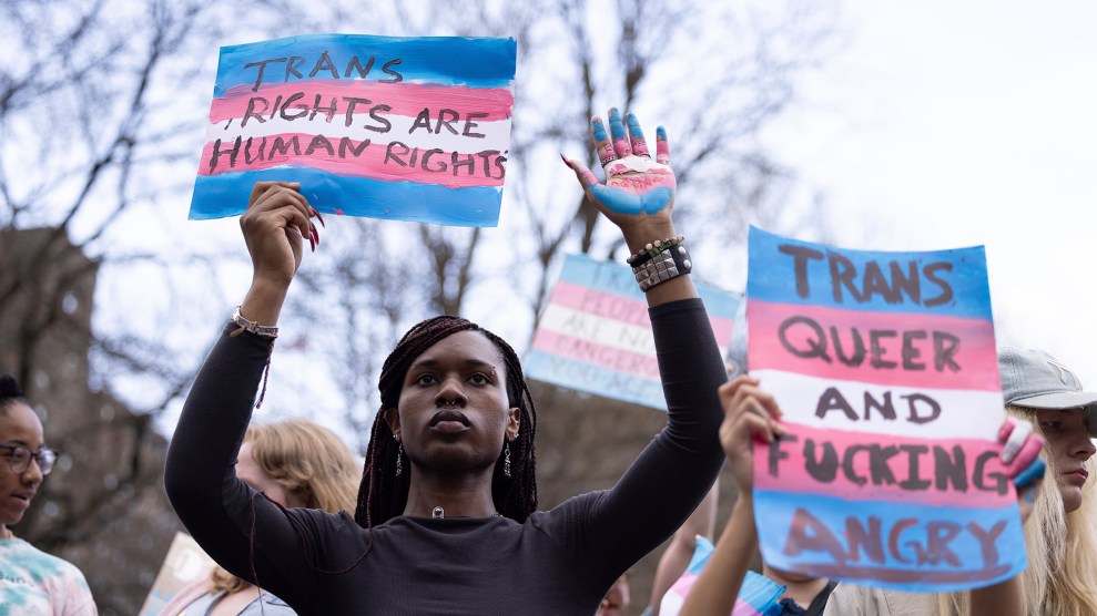 A Black person with long hair holds a sign that says "Trans Rights are Human Rights."