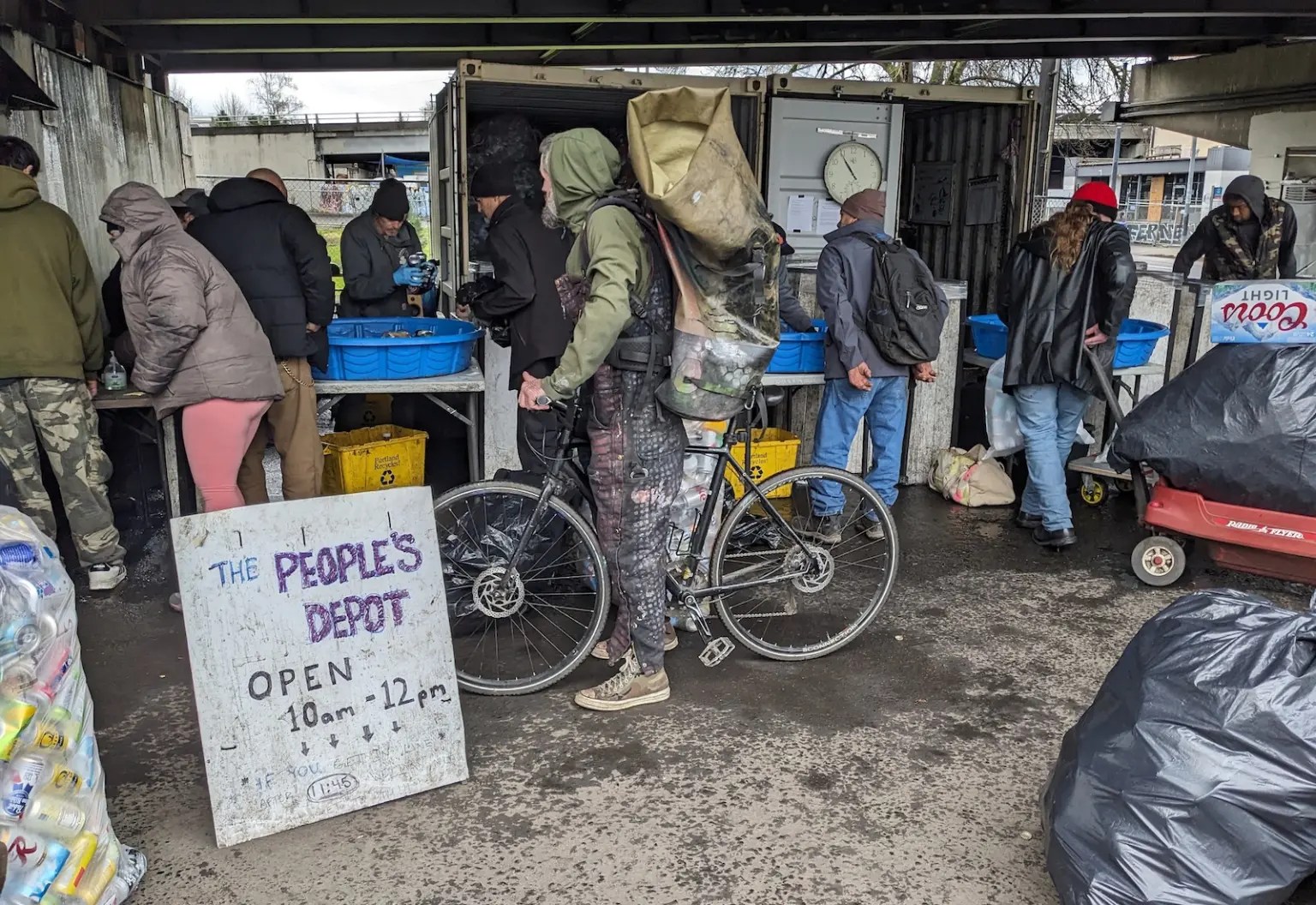 Folks line up at "The People's Depot." One holds a bike.