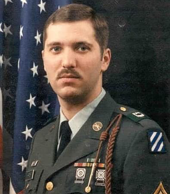 A formal portrait of a young James Harter, with brown mustache and short brown hair,  in an Army dress uniform in front of an American flag.