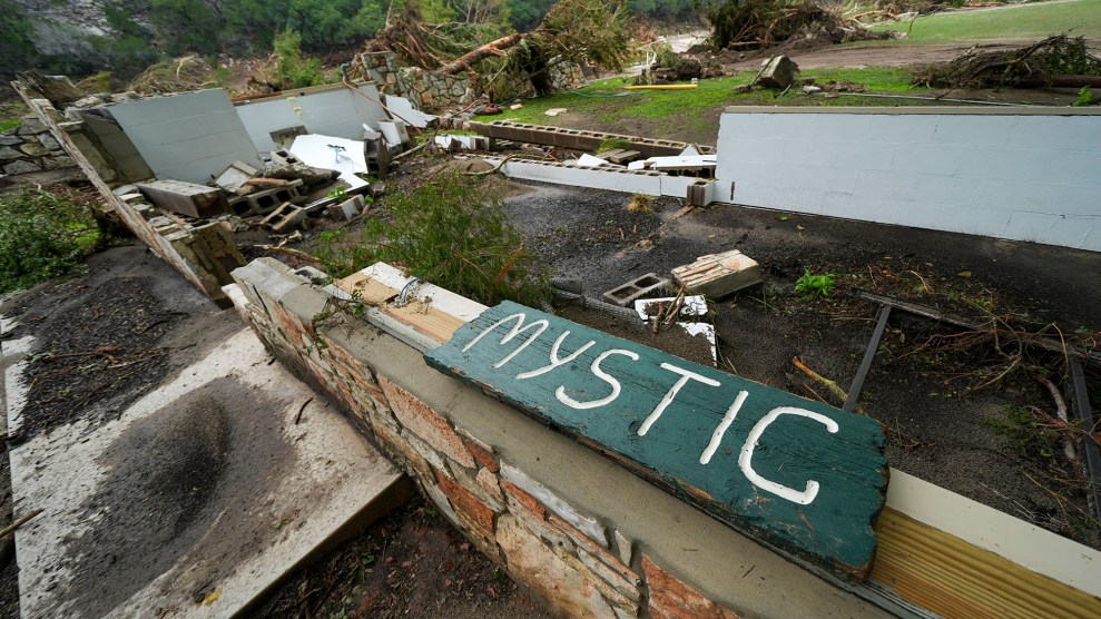 A wooden sign that reads "Mystic" lies on top of debris from a destroyed building.