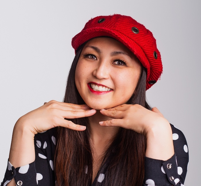 A Japanese American woman in a black polka dot shirt and red hat