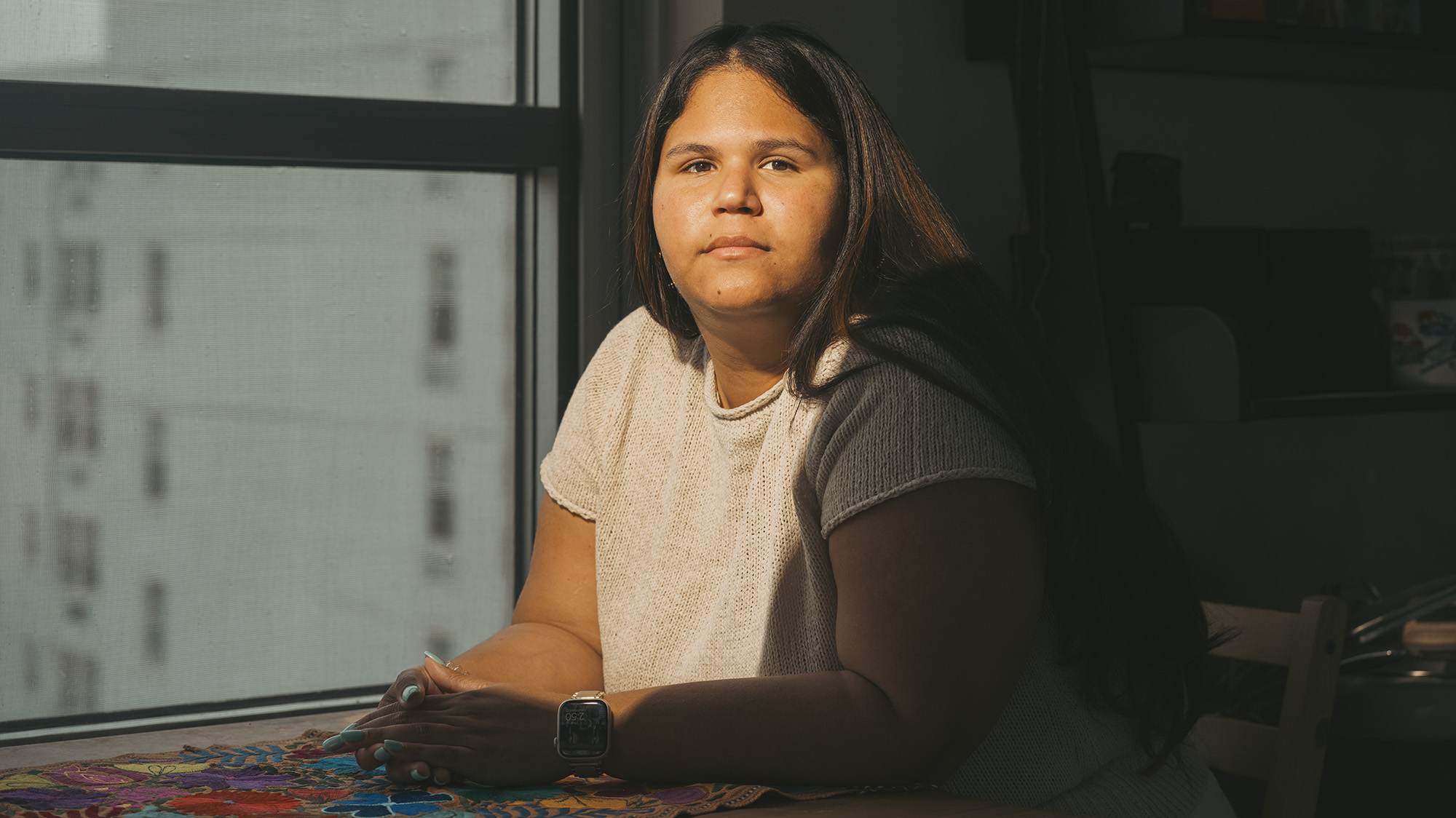 A woman faces the camera with her hands crossed.