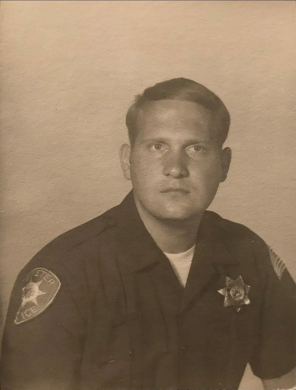 An official black-and-white portrait of a Caucasian man wearing an Exeter police uniform.
