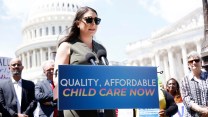 Portrait of Rep. Sarah Jacobs behind a sign that says "quality, affordable childcare now."