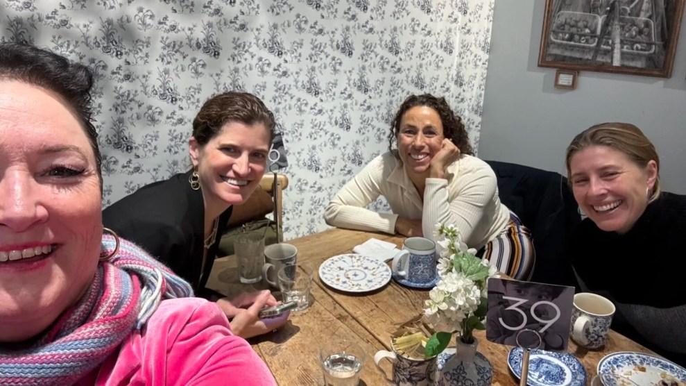 Four women sit around a table smiling