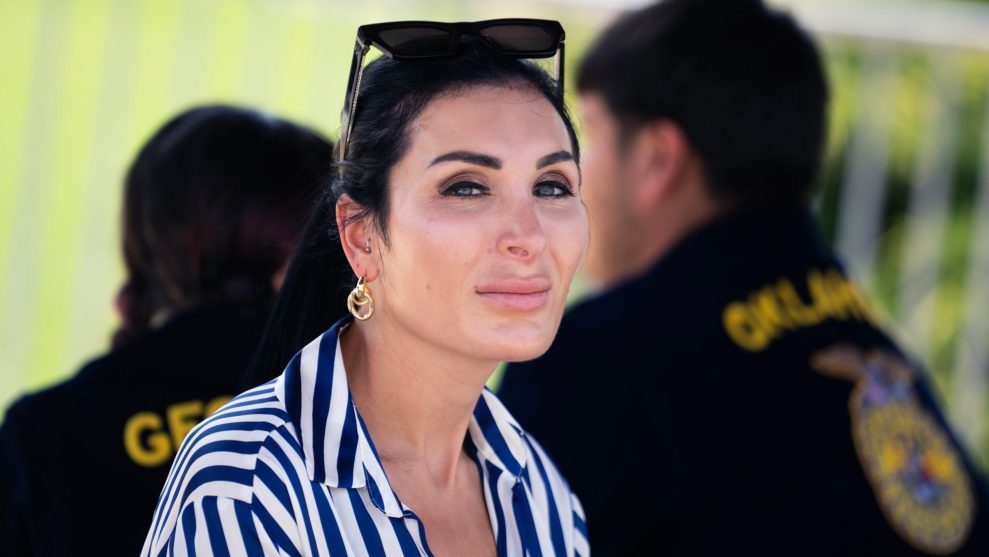 Laura Loomer wearing a blue-and-white striped shirt looking into the camera.