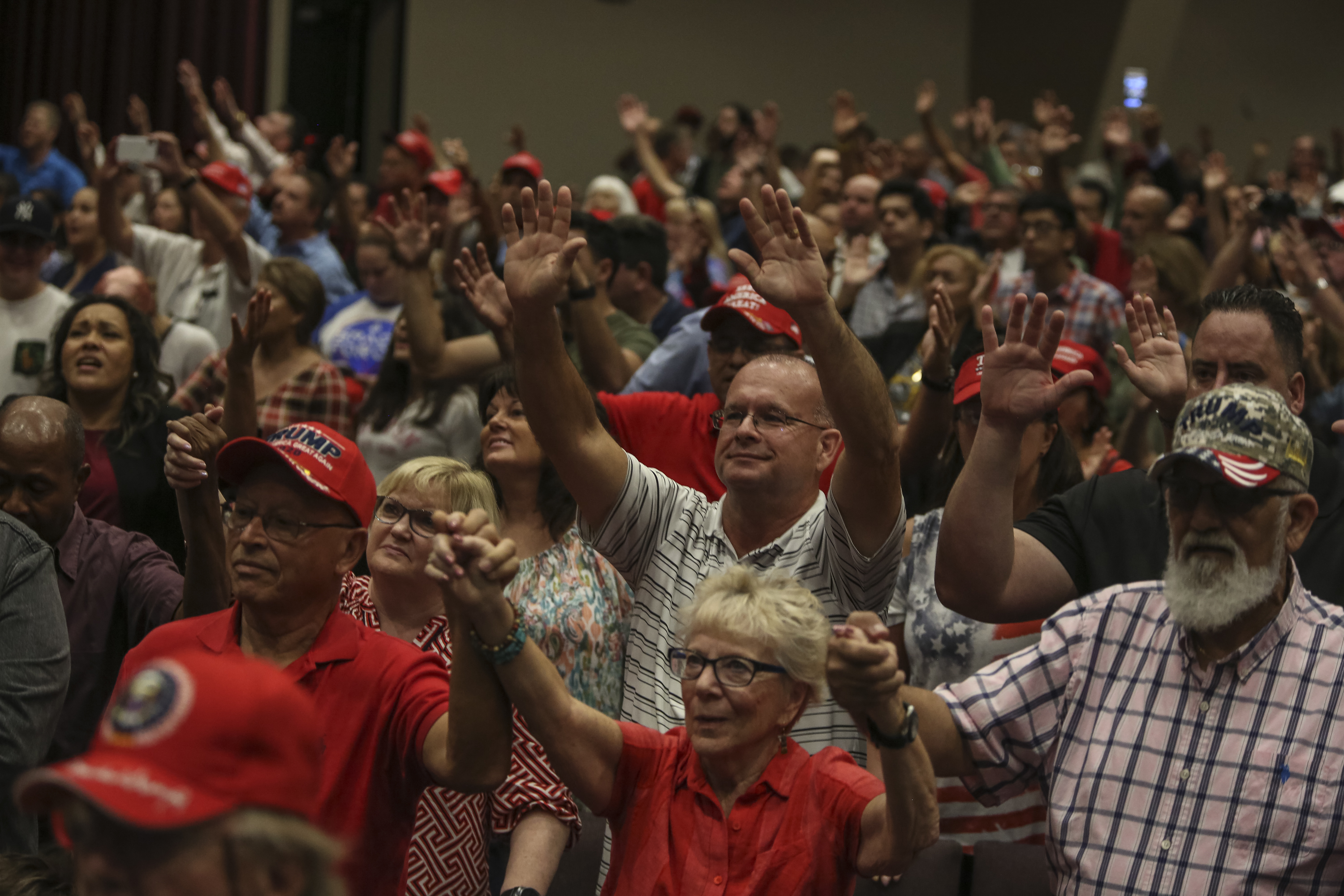 A crowd of people inside a church with hands raised.