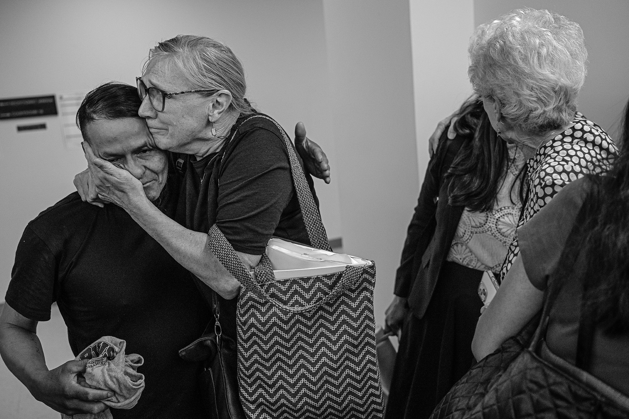 Two woman hug a man and a woman.
