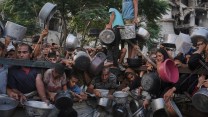 Palestinians struggle to get donated food at a community kitchen in Gaza City
