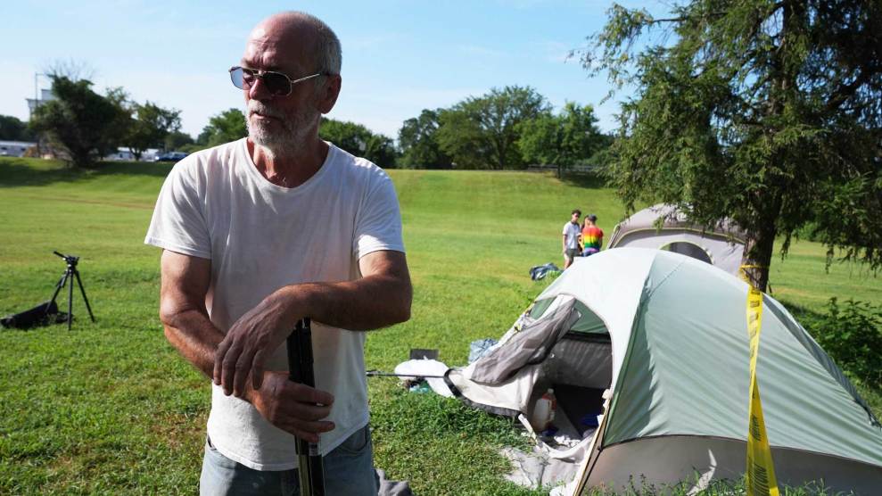 Bald man with sunglasses standing in a grassy lawn in front a tent