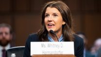 Whitney Hermandorfer sitting at a wooden table speaking into a microphone before the Senate Judiciary Committee.