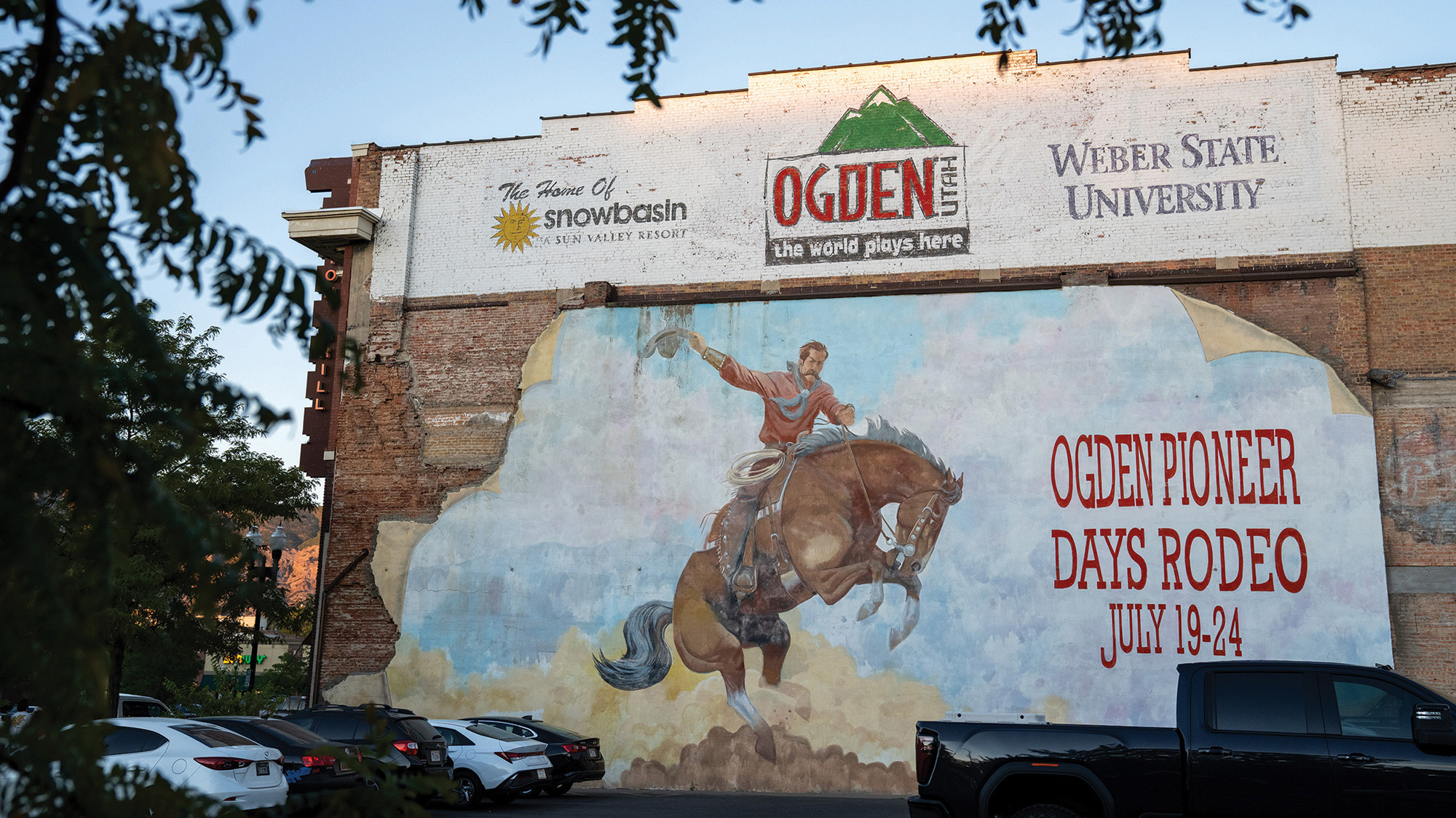 A mural on the side of a brick building depicts a rodeo rider on a bucking horse with the words, "Ogden Pioneer Days Rodeo, July 19-24."