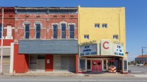Storefronts on an empty street. One brick, another yellow.
