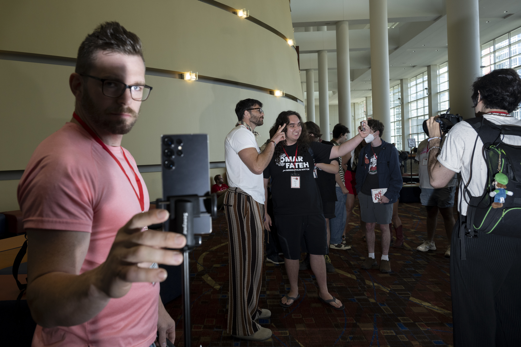 Man holding phone with a group of people behind him.