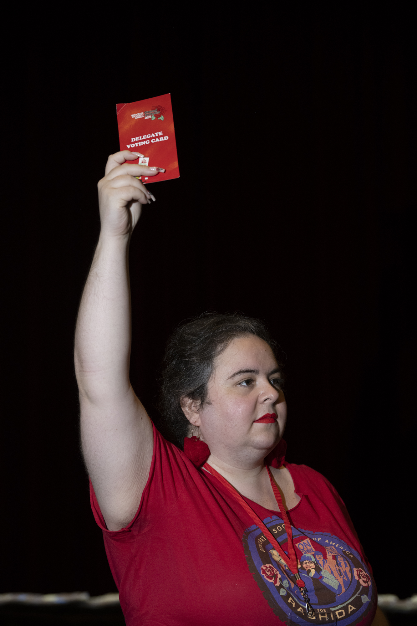 Portrait of woman with raised arm, holding a red card.