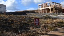 An empty lot with a wood-frame house with the sign "keep Lahaina lands in Lahaina hands"