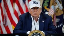 Donald Trump sits at a table behind a presidential seal. Beads of sweat are visible on his face.