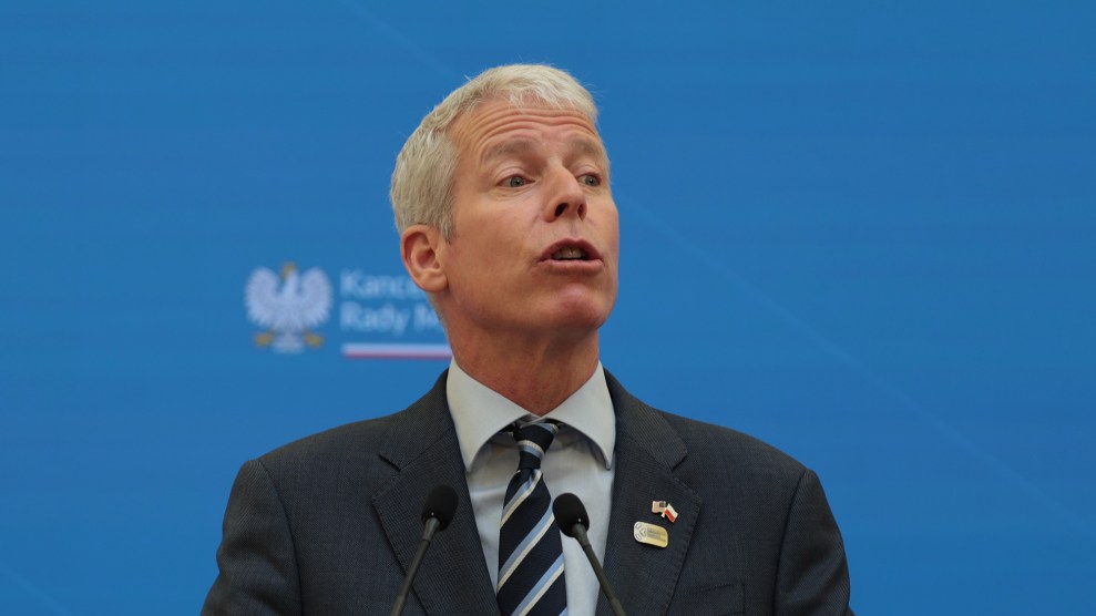 A white man with an open mouth. He wears a suit in front of a blue background.