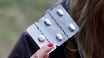 A woman holds up a pack of abortion pills, including misoprostol.