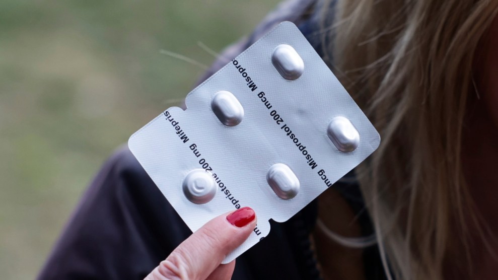 A woman holds up a pack of abortion pills, including misoprostol.