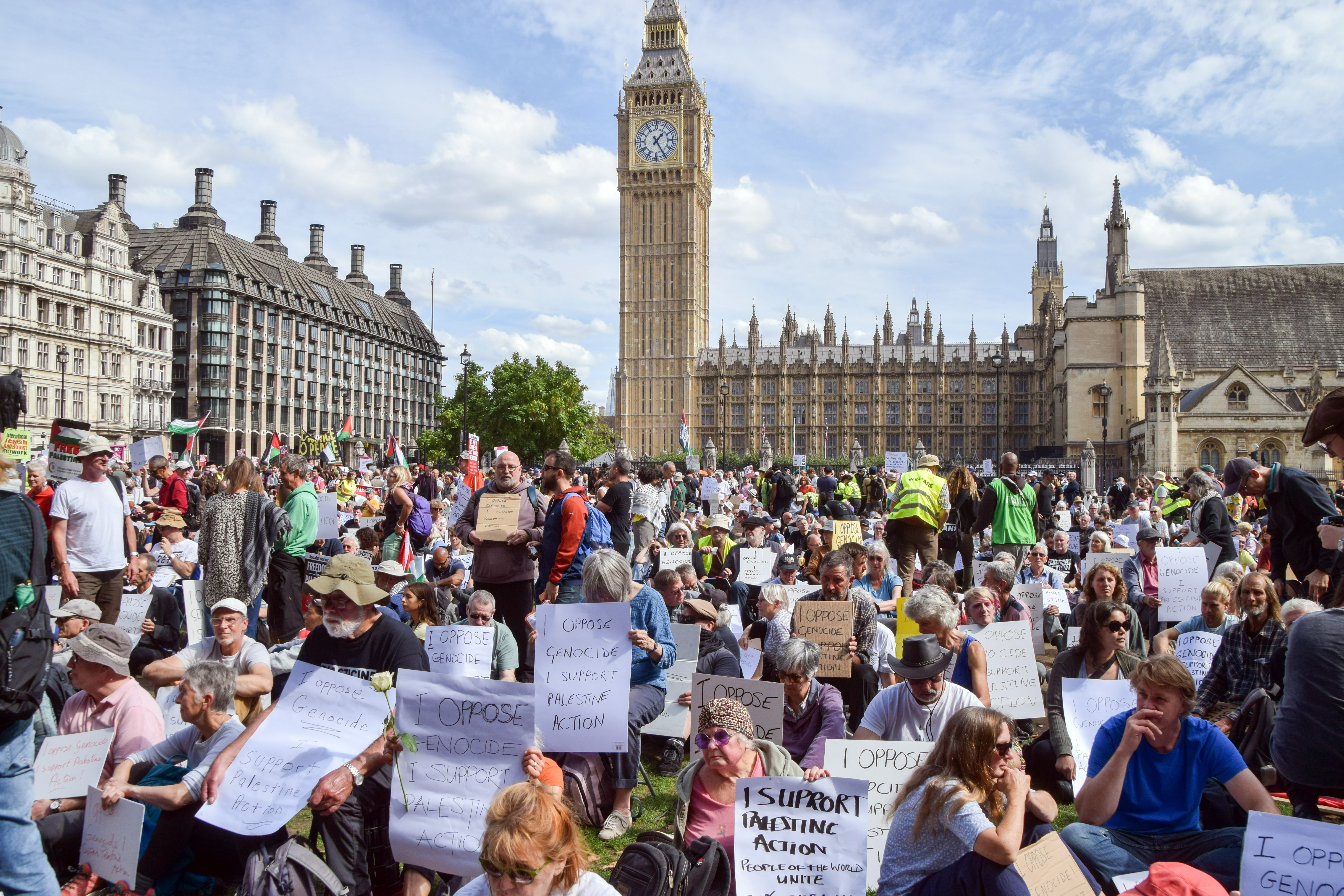 Protesters gather at Parliament Square holding signs.
