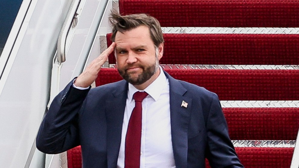 A waist up view JD Vance, a white man with chubby cheeks, descending the red carpeted staircase of an airplane