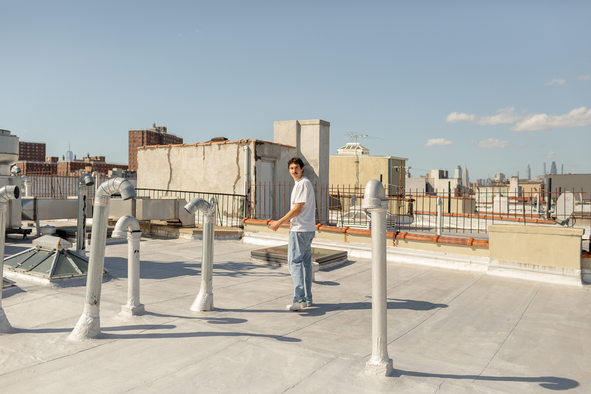 Man walking way, looking back, on an apartment rooftop on a sunny day.