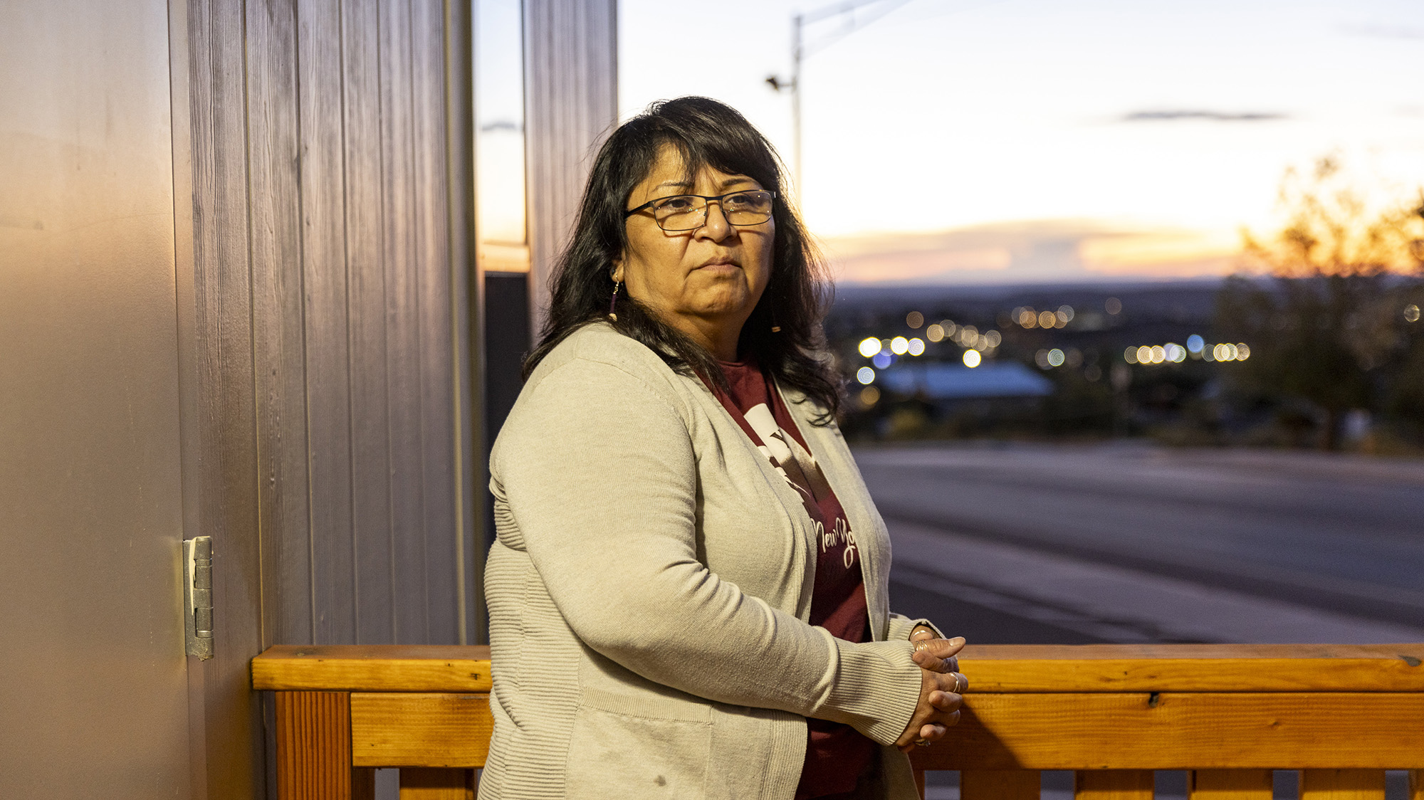 Marlo Kiyite leans against a wooden railing around dusk.