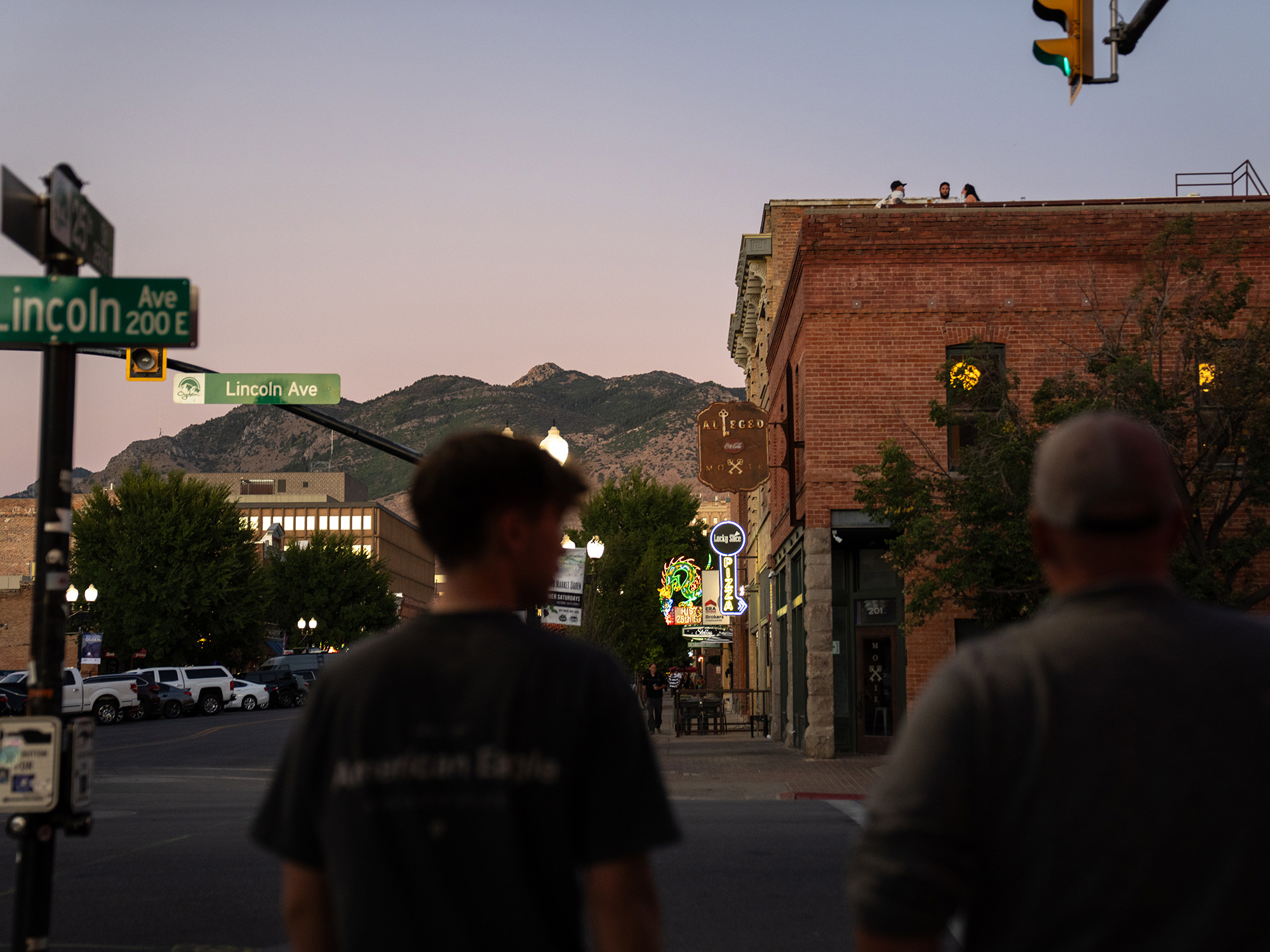 Mountains rise above a small-town main street. Neon shop lights are illuminated.