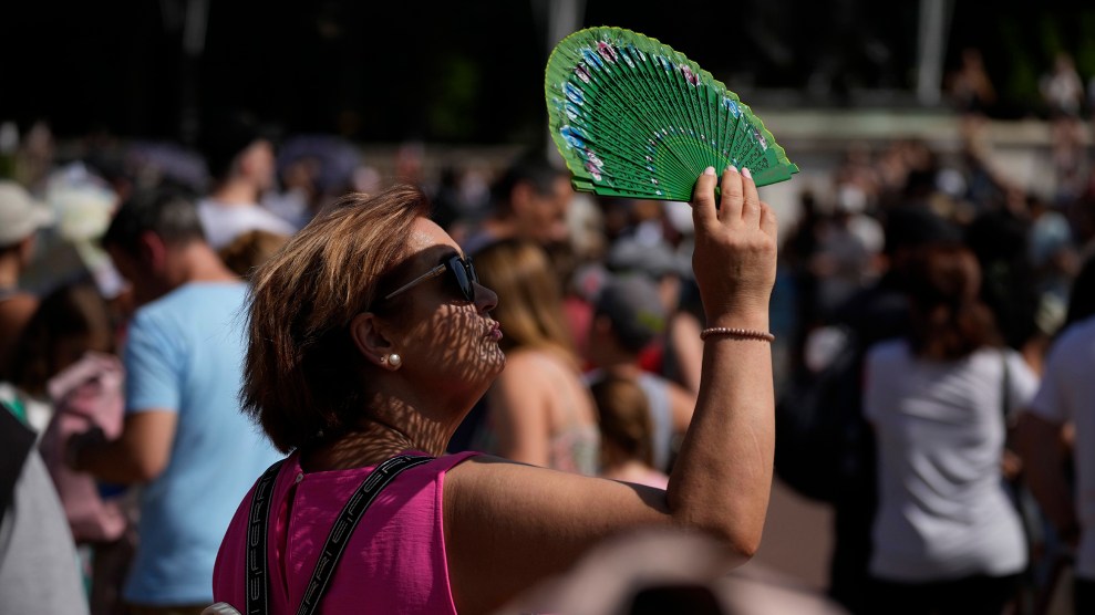 A woman holds a green hand fan over her face.