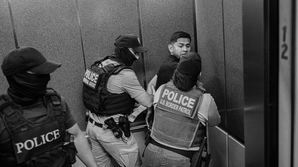 Federal agents press a man against a corner of an elevator as they detain him.