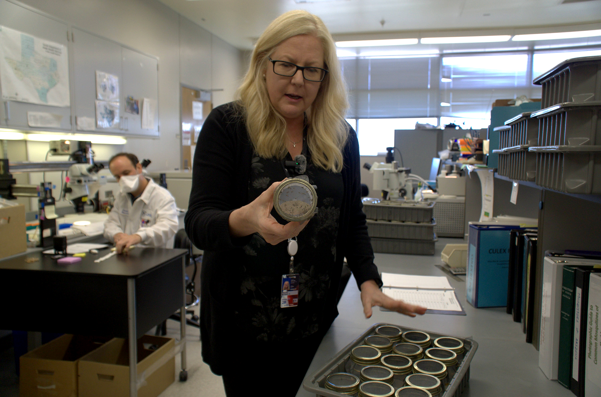 A blond woman looks at a petri dish.