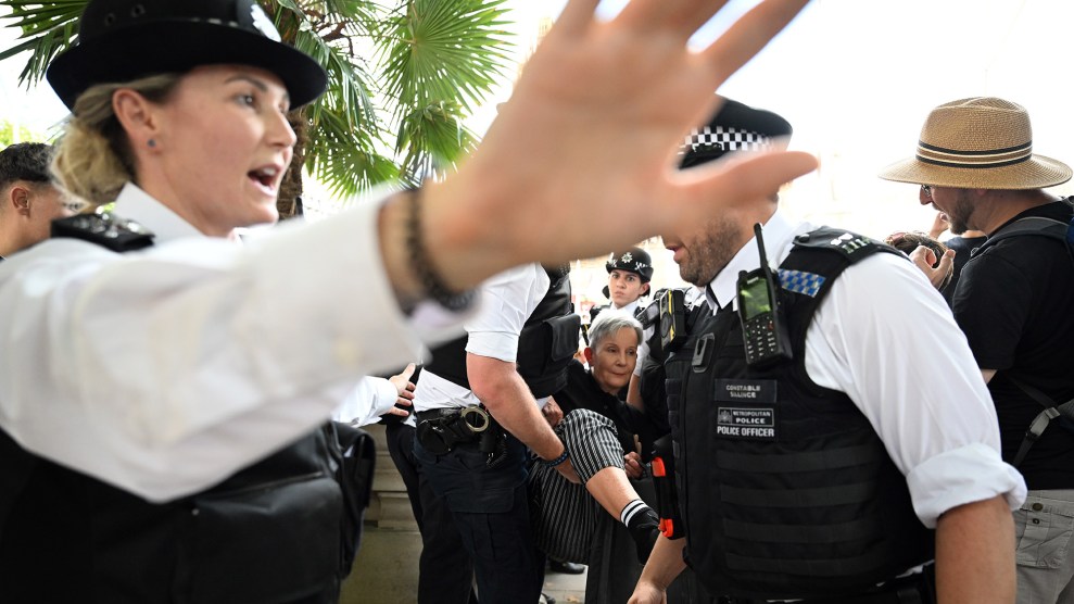 British police officer puts her hand up to try and block photographer from making image of woman getting arrested.