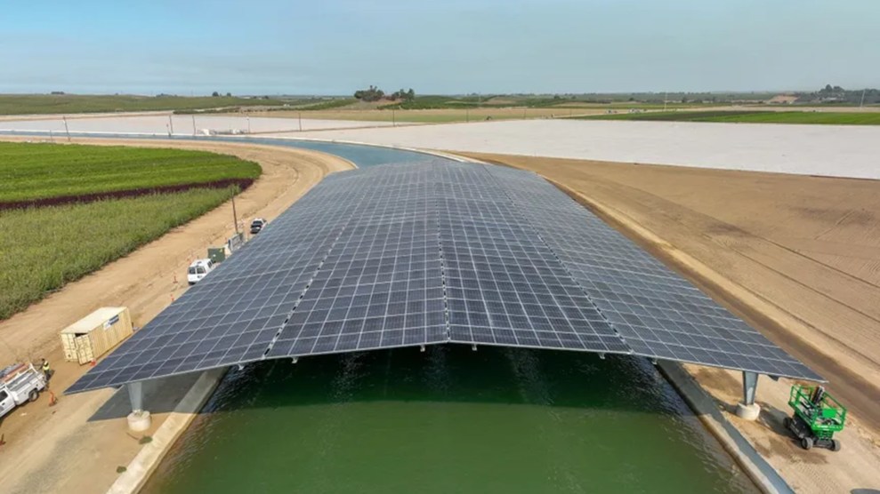 A solar panel over a large, green canal.