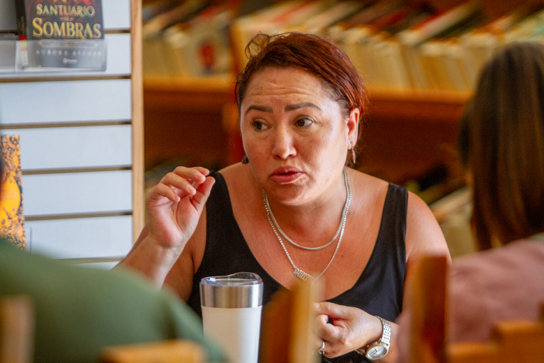 A woman with dark red hair speaks.