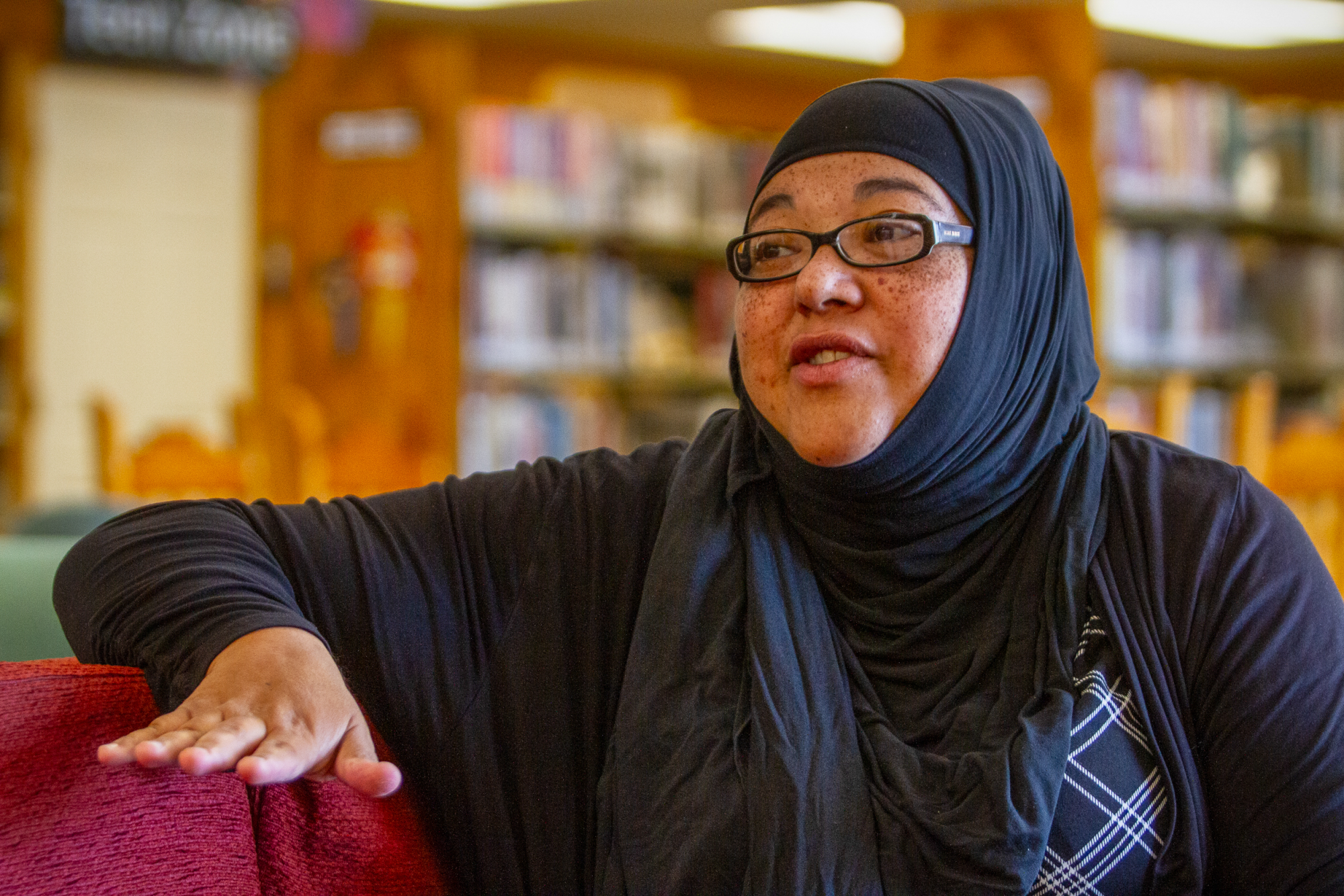 A woman wearing glasses and a hijab speaks 