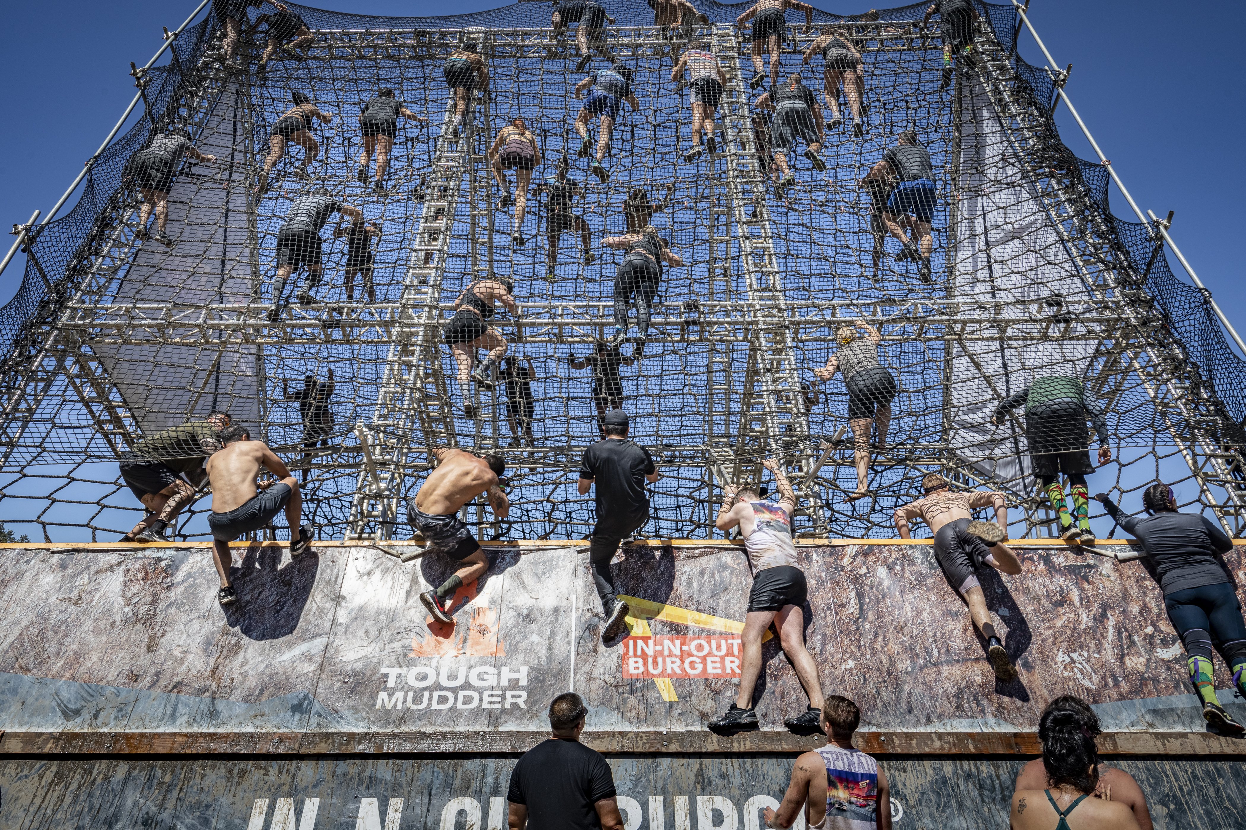 Dozens of people climb up a large rope ladder.