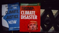 A red sign with Trump's face that reads: Trump: Climate Disaster