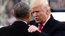 A photograph of Donald Trump speaking with Barack Obama, as his left hand is placed on Obama’s shoulder. Both men are wearing dark suits and overcoats.