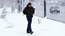 A person braces against the cold on a snowy street.