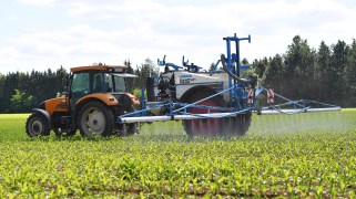 A farmer applies pesticides on a field with a tractor.
