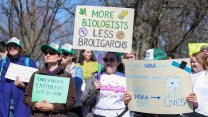 A person wearing a shirt that says ecologist holds a sign that says "More biologists, less broligarchs." Others surround them with similar science-themed signs.