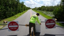 A National Park Service employee wearing a neon green shirt closes the entrance to a park.