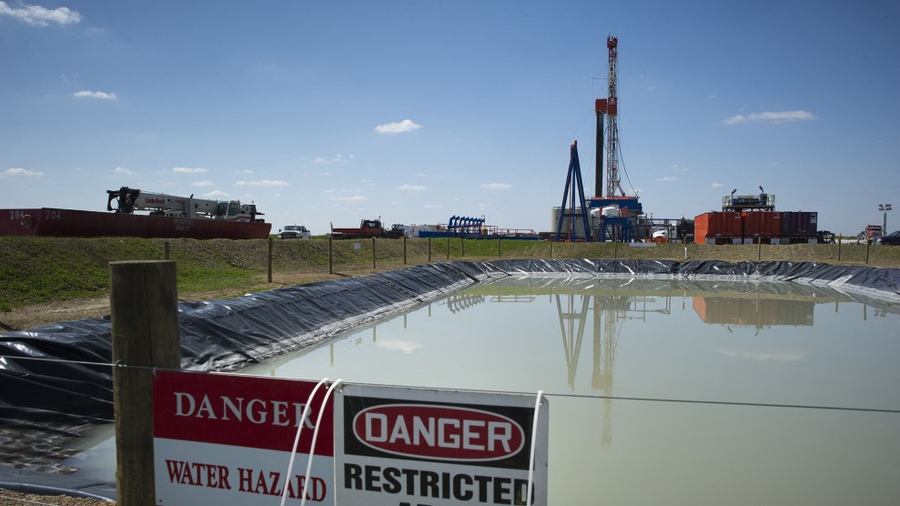 A drilling rig in front of an artificial pond with a "danger" sign in front of it.