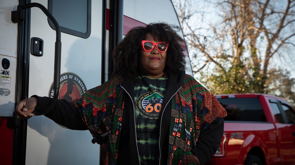 Portrait of African American woman wearing red glasses standing next to a camping trailer.