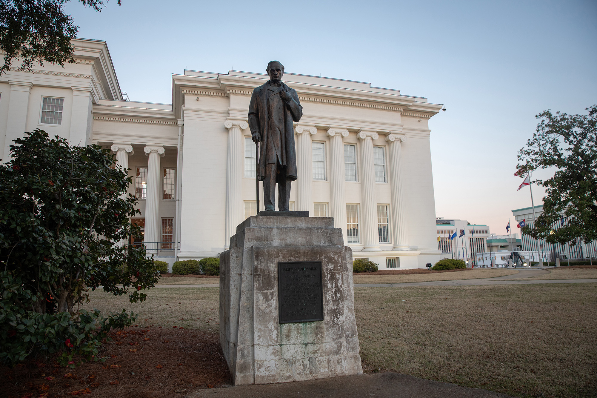 Statue of man in front of a colonial style building.