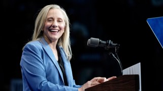 Abigail Spanberger, a white woman with blonde hair, at a lectern in a blue suit jacket.