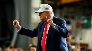 Donald Trump wearing a white USA hat and dancing.
